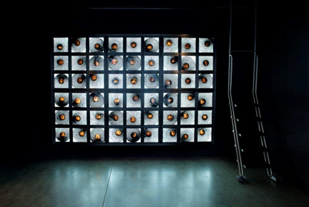 A room with a ladder and a wall adorned with illuminated drawers.