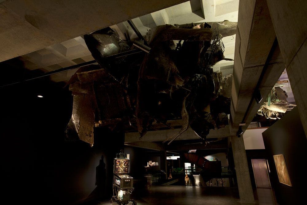 Dimly lit sculpture of debris suspended from the ceiling covered in dust.