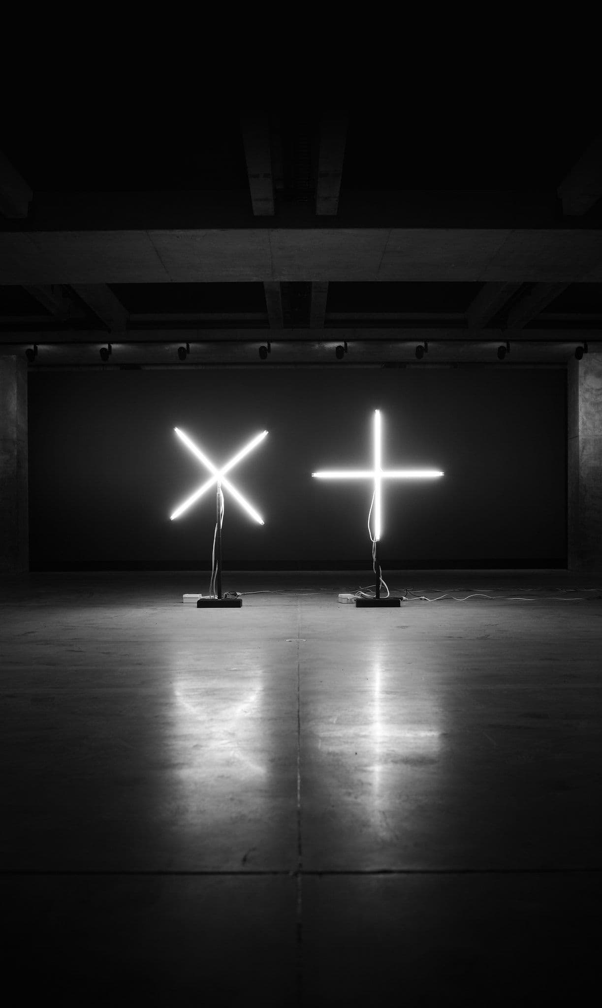 Illuminated cross and plus symbol in a darkened room