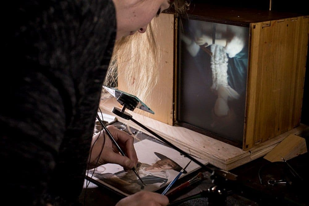 A person painting using the comparator mirror device.